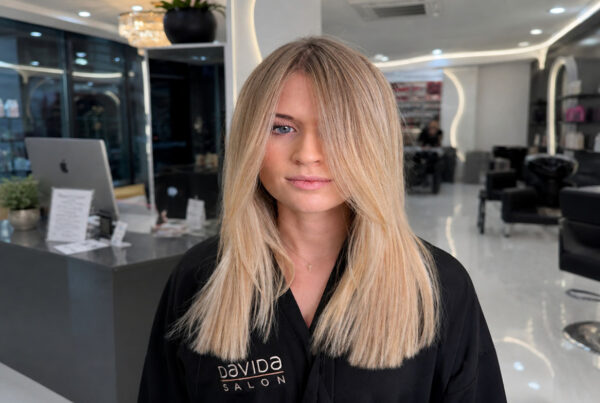 A woman showcasing smooth, sleek blonde hair following a professional keratin treatment at Davida Salon.