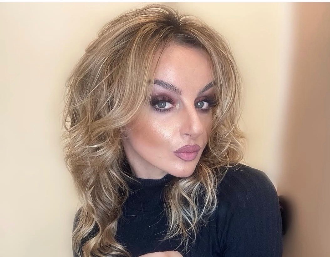 Woman with long, layered blonde hair in soft waves, styled with professional hair extensions at Davida Salon in NYC.